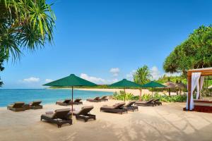 a beach with chairs and umbrellas and the ocean at Amarterra Villas Resort Bali Nusa Dua, Autograph Collection in Nusa Dua
