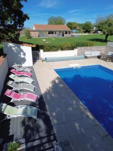 a row of lounge chairs next to a swimming pool at Chambres d'hôtes Les Rozières in Le Bourdet