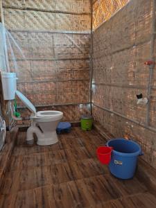 a bathroom with a toilet and buckets on a wooden floor at Hampi One Love in Hampi +34 photos