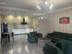 ein Wohnzimmer mit grünen Sofas und eine Küche in der Unterkunft Hotel Florencia in Mzcheta