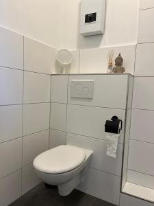 een witte badkamer met een toilet en een spiegel bij Stillvolle Stadtwohnung am Klinikum Bielefeld, zentral und mit Parkplatz! in Bielefeld