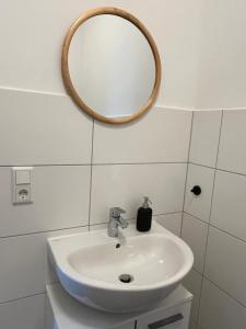 een badkamer met een wastafel en een spiegel aan de muur bij Stillvolle Stadtwohnung am Klinikum Bielefeld, zentral und mit Parkplatz! in Bielefeld