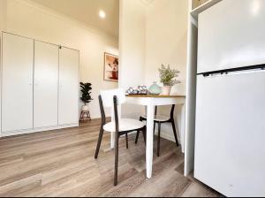 a dining room with a white table and chairs at Coastlight - Modern Beachside Studio in Woonona in Woonona