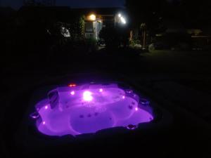 a purple hot tub with lights in a yard at night at ArtRock Studio in Radovljica