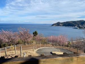 a view of the ocean from a hill with trees at StellaMarina~海の星　ATAMI in Shimo-taga
