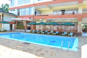 una piscina frente a un hotel con sillas y sombrillas en Golf Hotel Kakamega, en Kakamega