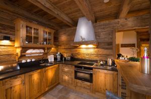 a kitchen with wooden cabinets and a counter in a cabin at Chaletdorf Auszeit in Hüttschlag