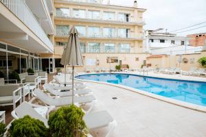 a hotel swimming pool with lounge chairs and an umbrella at Hotel S'Agoita in Platja d'Aro