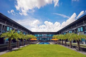 una vista exterior de un edificio con palmeras y una piscina en Amari Buriram United, en Buriram