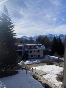 un patio cubierto de nieve con una casa en el fondo en Hostdomus - Grand Villard Suite, en Sauze dʼOulx