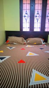 a bed with colorful comforter with stained glass windows at Sri BALAJI homestay Guest house in Tiruvannāmalai