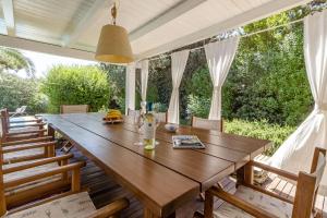 a wooden dining table on a deck with chairs at CASAVIVA - Villa con piscina privata a Stintino in Stintino