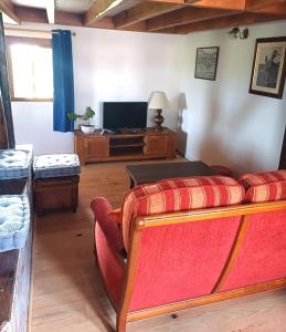Una sala de estar con un sofá rojo y un televisor. en Maison en campagne style western, en Halluin