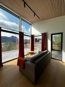 a living room with a couch and large windows at Efjord and Stetind Resort - Cabin Kulhorn in Ballangen