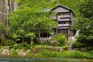 ein Haus neben einem Fluss neben einem Gebäude in der Unterkunft Hoo!Hoo! in Ono