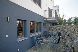 eine Terrasse mit 2 Stühlen und einem Tisch neben einem Gebäude in der Unterkunft Casa Fortuna Bodensee in Lindau-Bodolz