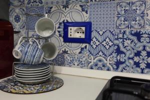 a pile of dishes on a plate in a kitchen with blue and white tiles at Sul Mare Apartment in Capo dʼOrlando