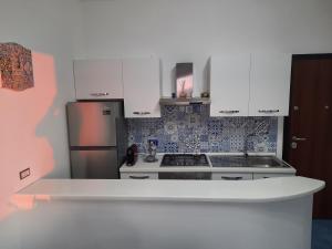 a kitchen with white cabinets and a stainless steel refrigerator at Sul Mare Apartment in Capo dʼOrlando +2 photos