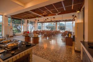 a large room with tables and chairs and windows at La Perle River Resort By Excel Hotels & Resorts in Rāmnagar