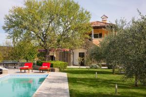 a house with a swimming pool and two red chairs at Villa Momiano with Private pool in Momjan