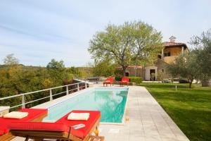 a swimming pool with red chairs and a house at Villa Momiano with Private pool in Momjan