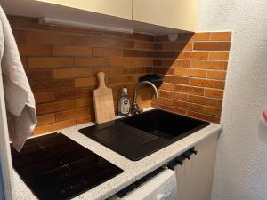 - une cuisine avec un évier et un mur en briques dans l'établissement Serre Chevalier Chantemerle Appartement pour 4 personnes, Résidence les Mélèzes, à Saint-Chaffrey