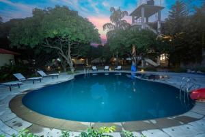 a swimming pool with chairs and a sunset in the background at La Perle River Resort By Excel Hotels & Resorts in Rāmnagar