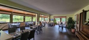 a dining room with tables and chairs and windows at Hôtel du Lac in Lacapelle-Viescamp