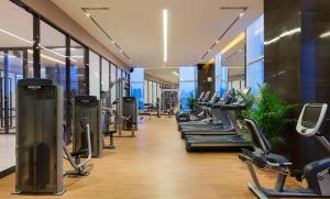 a gym with a row of treadmills and machines at Wanda Realm Hotel Wuhu in Wuhu