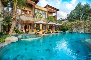 乌布Bliss Ubud Spa Resort的一座带度假村的建筑前的游泳池