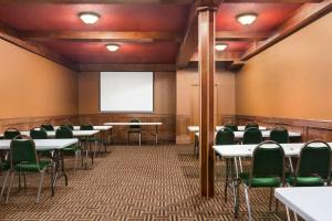 una sala de conferencias con mesas, sillas y una pantalla en Travelodge by Wyndham Meadow Lake, en Meadow Lake