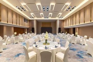 a large banquet hall with white tables and white chairs at Wyndham Garden Rizhao Donggang Resort in Rizhao