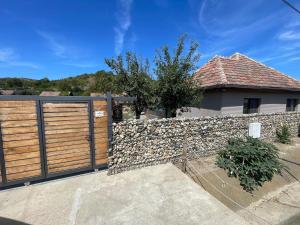 a house with a wooden fence and a stone wall at MOGA House in Tîrnăveni