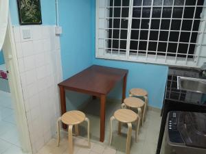 Una mesa pequeña y cuatro taburetes en una cocina. en Ns Guest House Puchong, en Puchong