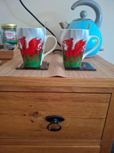 two cups sitting on top of a wooden dresser at 1A Butty Bach in Pembrokeshire