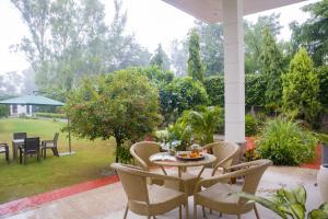 a patio with a table and chairs and a garden at Alaya Stays 3 BHK Pet friendly with Pvt Pool - Daffodil in New Delhi