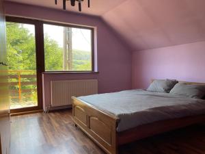 a bedroom with a bed and a large window at Cabana Micesti in Miceşti