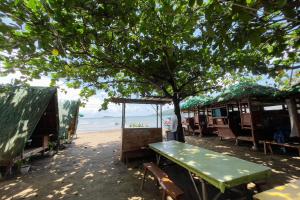 a picnic table on the beach under a tree at Villa Espinoza Beach Resort Nasugbu in Nasugbu