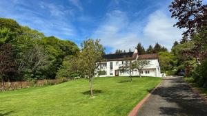 a white house with a grassy yard in front at Drumfin Cottage in Elgin
