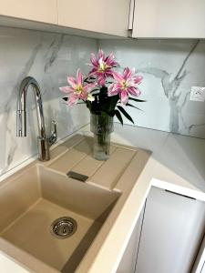 a vase of pink flowers sitting on a kitchen sink at SILVER apartment - Rezidencia Bojnice in Bojnice +16 photos