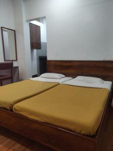 two beds in a room with a yellow bedspread at Hotel Parth Residency in Kolhapur