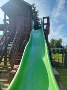 a green slide in front of a playground at Domki na Chabrowej in Augustów