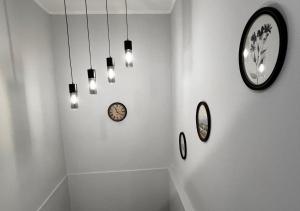 a white room with clocks on the wall and lights at Chachino Guesthouse -5 Mins walk to Train & Bus Station in Agualva +68 photos