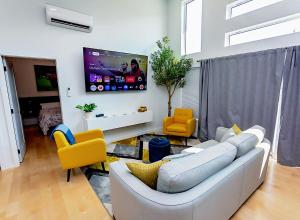 a living room with a white couch and yellow chairs at LuxQuarters Bumbleberry Guest House in Kitimat