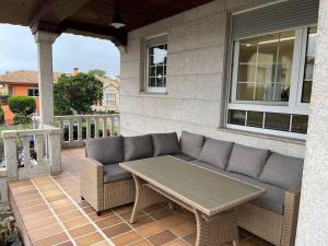 eine Terrasse mit einem Sofa und einem Tisch auf einer Veranda in der Unterkunft CasaPlayaPatos,com Panxón in Nigrán