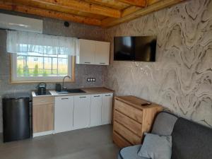 a kitchen with white cabinets and a stone wall at Domki U Joanny - Sarbinowo 900 m do morza in Sarbinowo