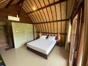 ein Schlafzimmer mit einem Bett in einem Zimmer mit einem Dach in der Unterkunft Babakan Unda Cottage in Semarapura