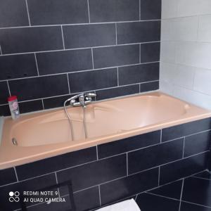 a bath tub in a bathroom with black tiles at Nuitée ZEN in Montigny-le-Chartif +11 photos