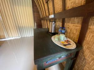 einen Tisch mit einem Teller und zwei Tassen drauf. in der Unterkunft Babakan Unda Cottage in Semarapura