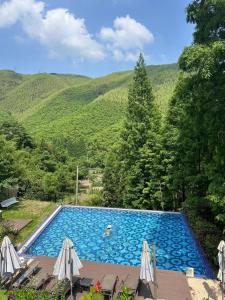 a swimming pool with mountains in the background at Moganshan Arcadia Resorts in Deqing